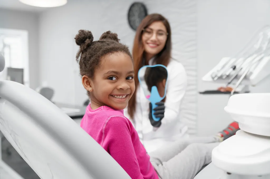 Little girl visiting the dentist and looking into a mirror